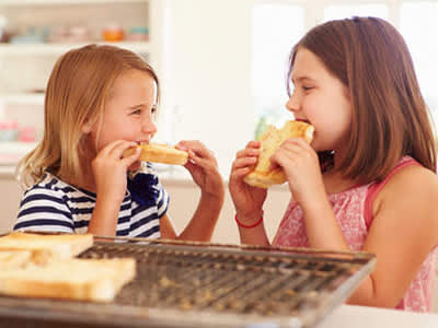 年轻的姐妹们在厨房里吃烤面包。
