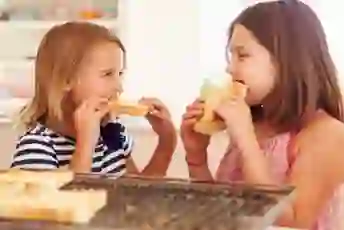 年轻的姐妹在厨房里吃烤面包。