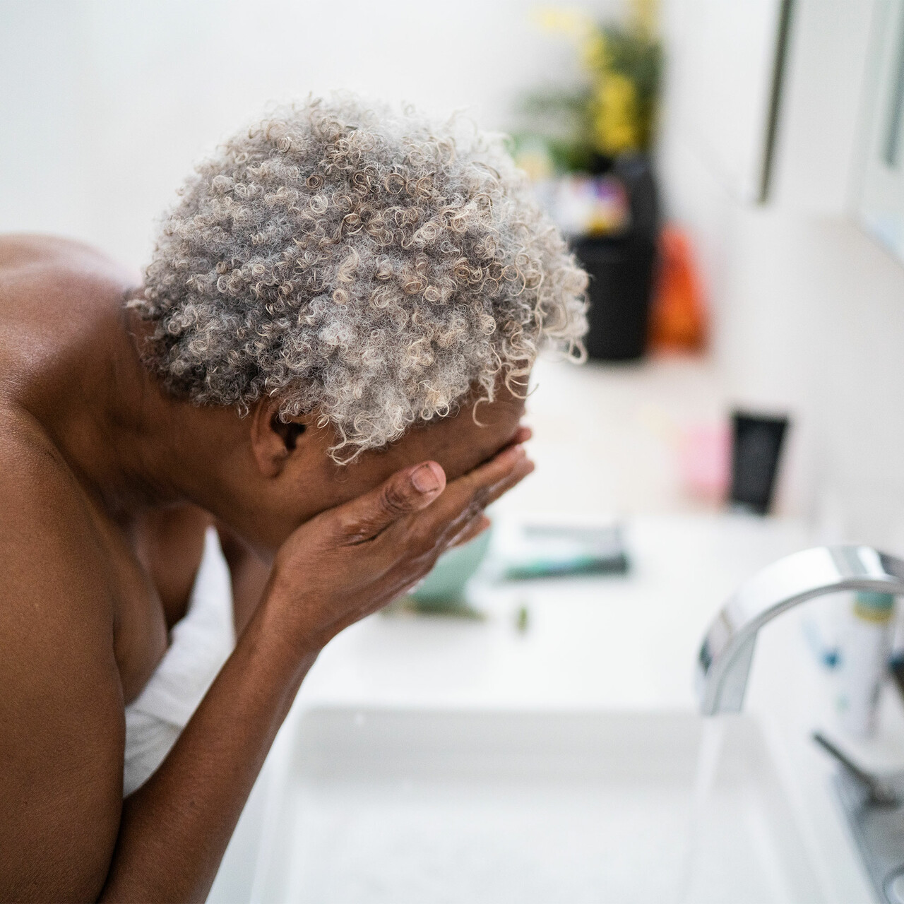 一个妇女在洗她的脸在一个水池