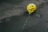 deflated smiley face balloon in the street