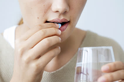 女人吞咽药片。