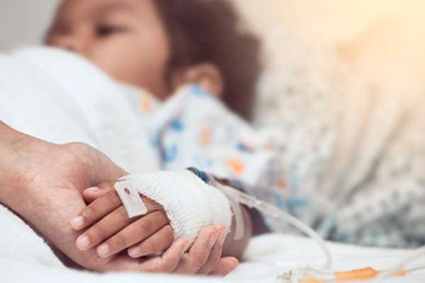 家长在病床上牵着小孩的手。