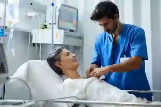 躺在病床上的女人，有护士在照顾她。