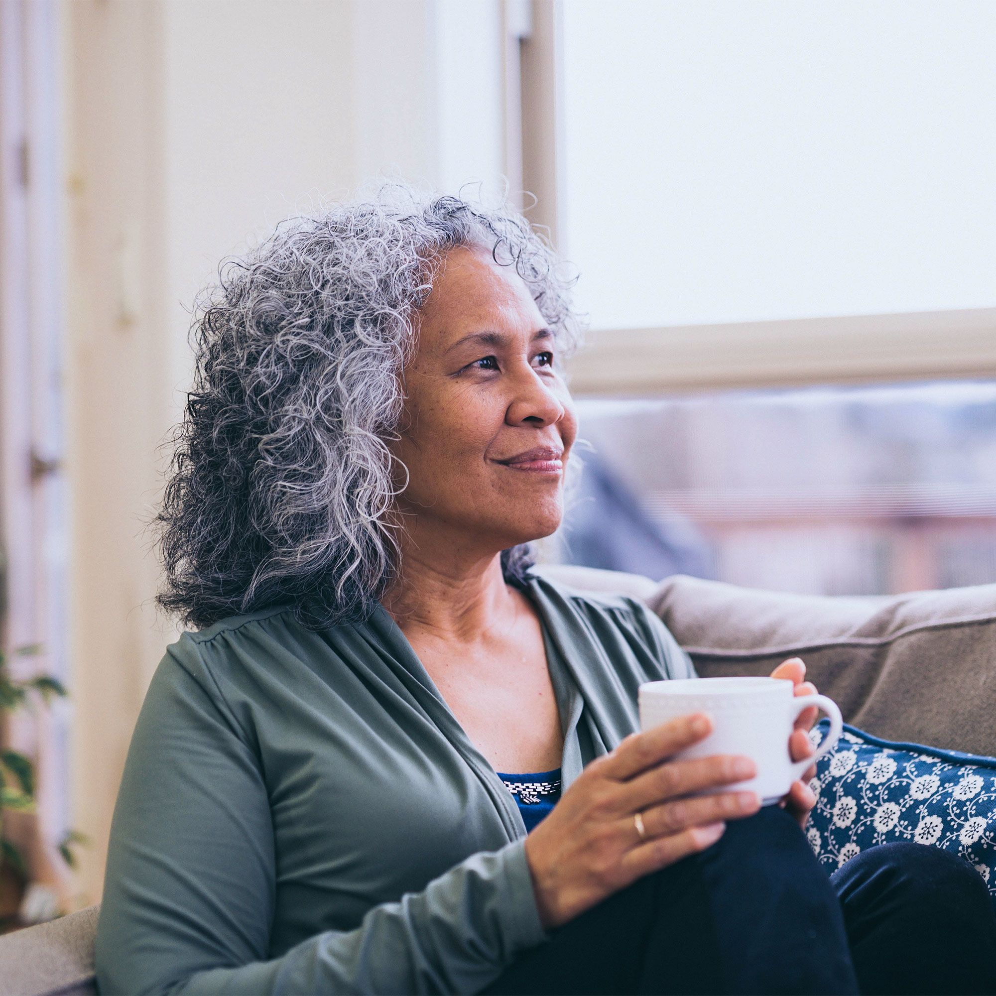 一个女人拿着杯子，看着窗外