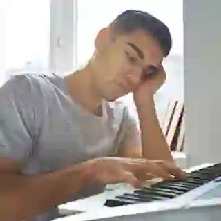Man uninspired to play music on his keyboard.