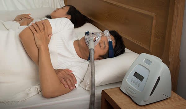 男子与他睡使用CPAP呼吸机睡眠呼吸暂停穿着。