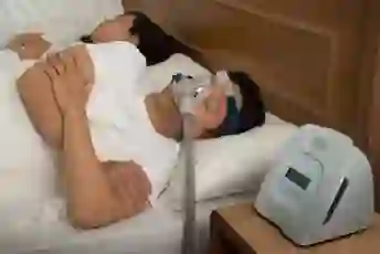 睡眠呼吸暂停的男人在睡觉时使用CPAP机。