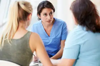 女医生与母亲和少女交谈。