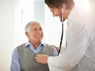 医生听着微笑的老人的心。