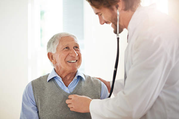 医生听着微笑的老人的心。