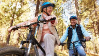 高级夫妇骑自行车，互相微笑。