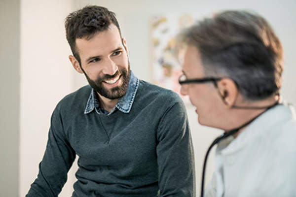 Man talking to his doctor about treatment for rheumatoid arthritis.