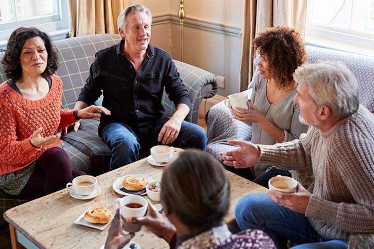 Middle age friends having a discussion in a living room.