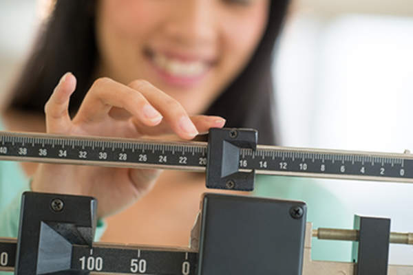 微笑的女人在调整体重秤。