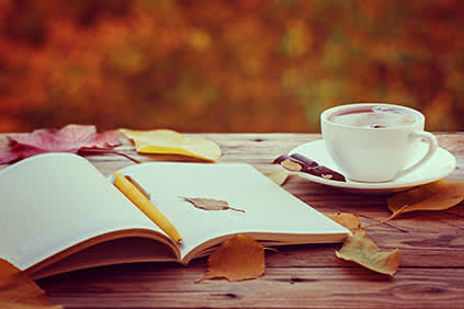 打开日记和一杯被秋天落叶覆盖的茶。