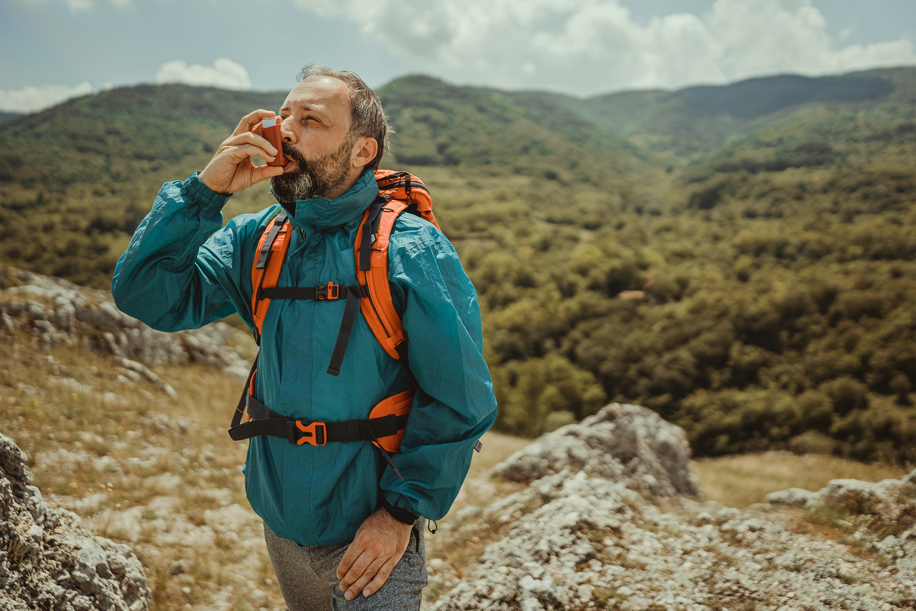 成熟男人使用哮喘吸入器救援期间攻击在大自然中散步