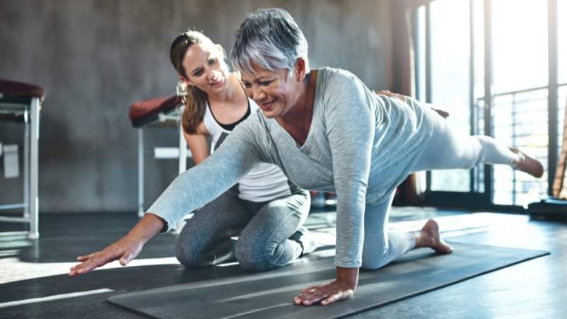 年轻女性在健身房帮助年长女性
