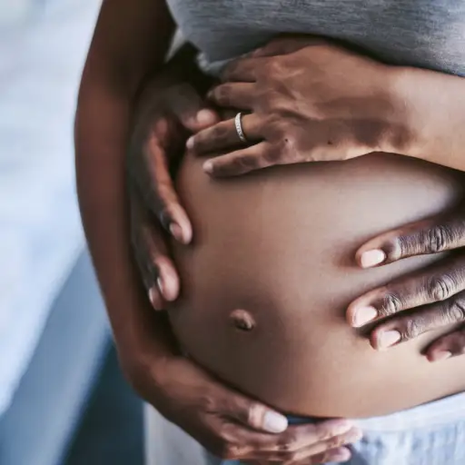 男人和女人的手围绕着怀孕的肚子