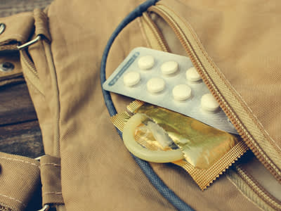 Birth control pill and condom peeking out from pocket.
