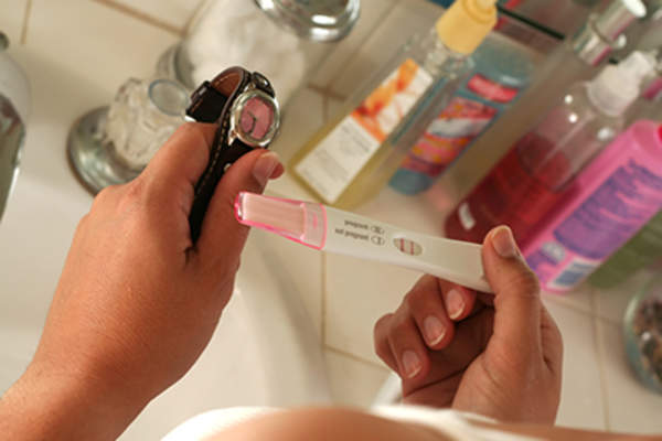 Woman using a watch and waiting to read pregnancy test.