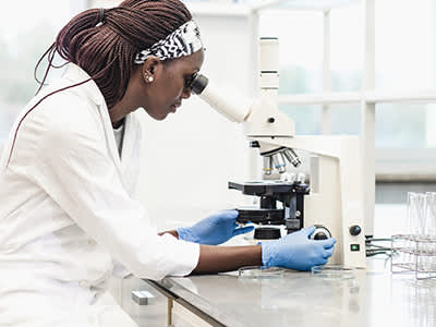 在实验室里用显微镜观察的女科学家。
