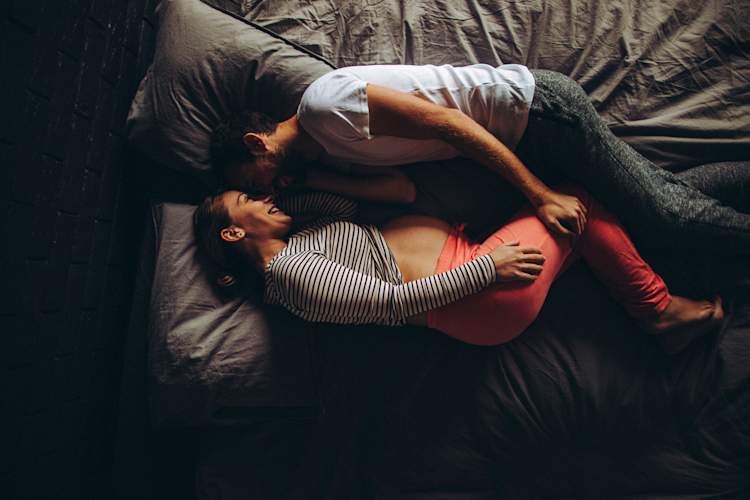 情侣在床上,女人怀孕和微笑