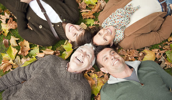 家庭躺在秋天的树叶在公园里。