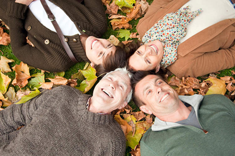 一家人躺在公园里的秋叶上。