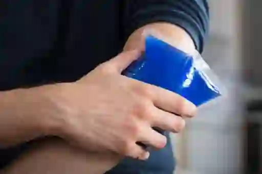 man applying ice pack to arm