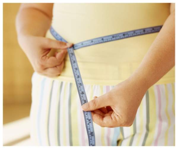 女人衡量她的腰，检查她的瘦身进展。