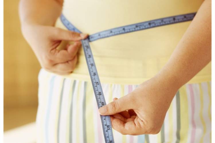 女人衡量她的腰,检查她的瘦身进展。