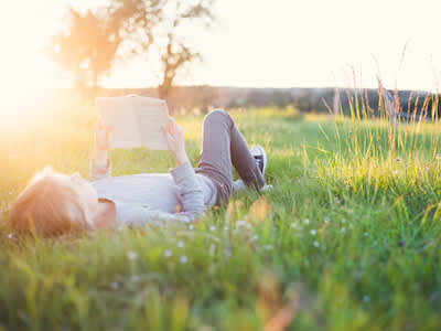 女孩躺在田野里看书。