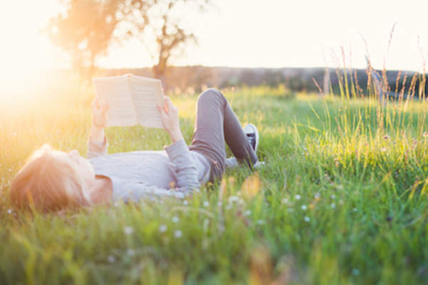 女孩躺在田野里看书。
