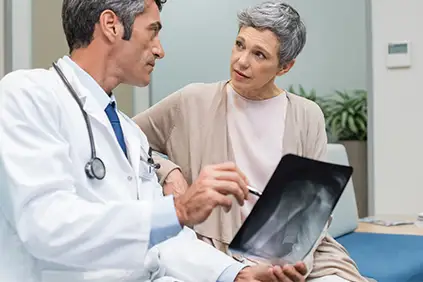 患有骨质疏松症的妇女拿着x光片与医生交谈。