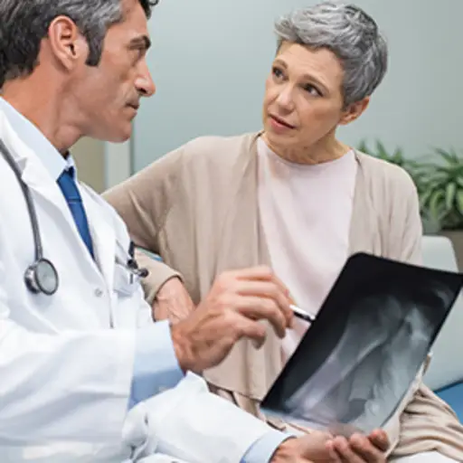 患有骨质疏松症的妇女拿着x光片与医生交谈。
