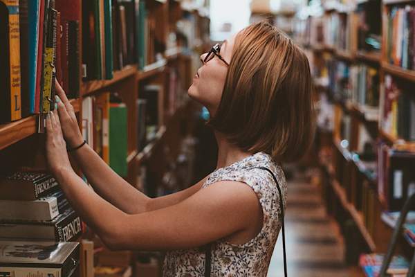 通过书籍在图书馆浏览的女人