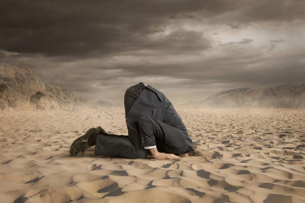 逃避概念男人把头埋进沙子里。