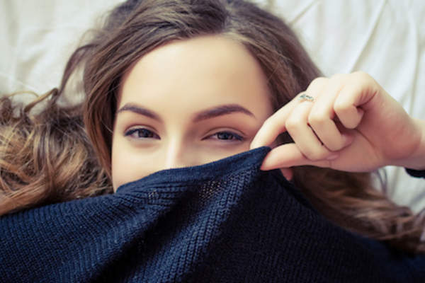 Young woman covering her face with sweater