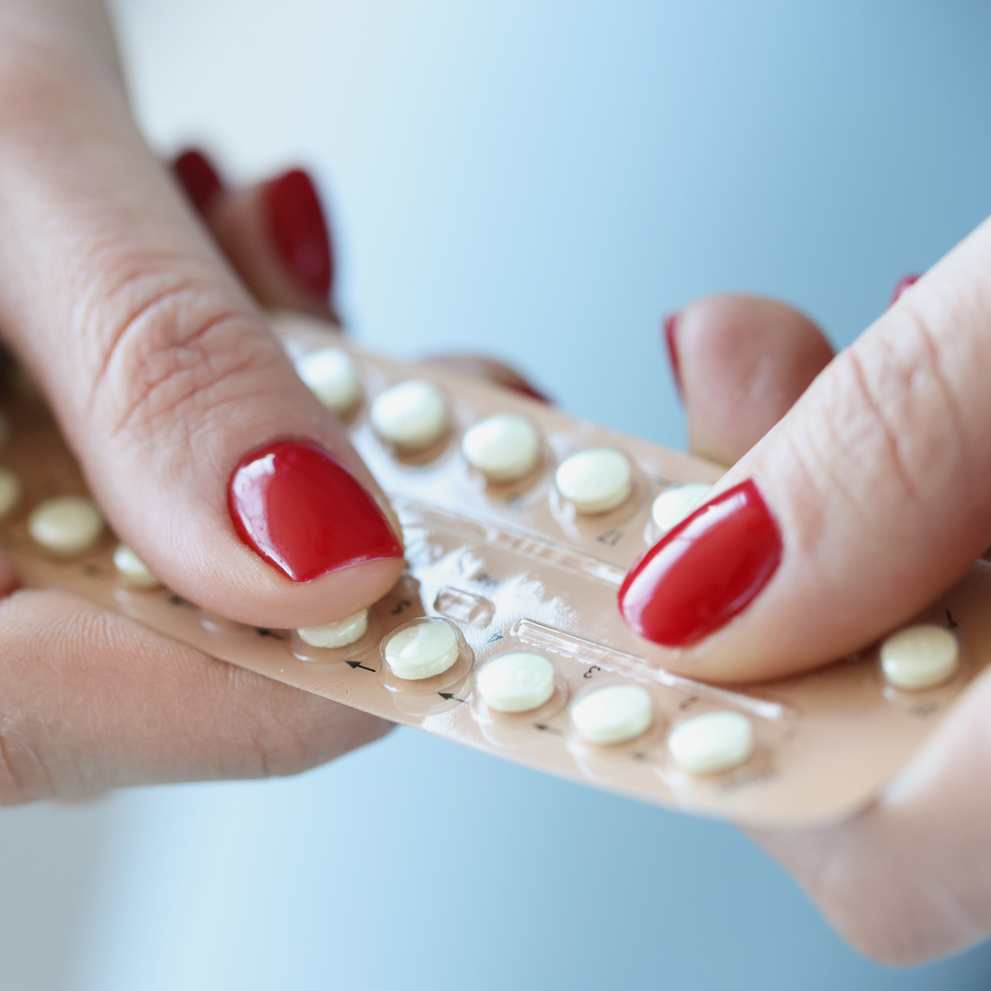 妇女的手拿着水泡包装的避孕药