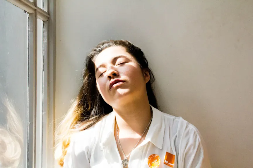 有眼睛的年轻疲乏的妇女在阳光下关闭了