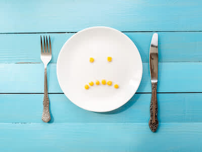 8个皱着眉头的玉米小丸子，放在白色的餐盘上，放在刀叉之间。