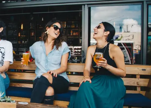 两个女人笑和喝啤酒