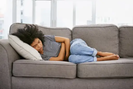 一个年轻女人躺在沙发上胃痛