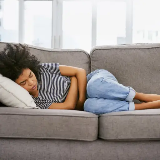 一个年轻女人躺在沙发上胃痛