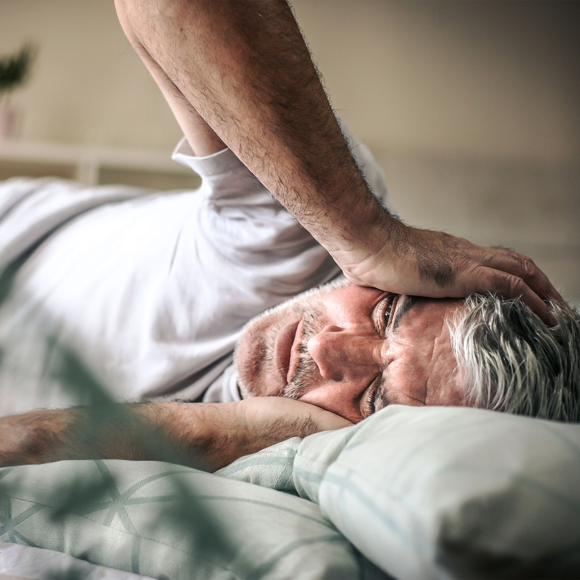 一个男人躺在床上摸自己的脸