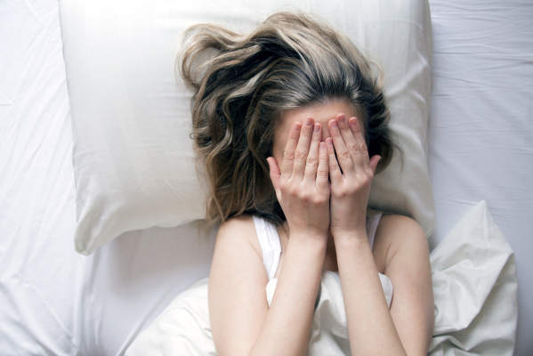 抑郁的女人在床上。年轻女性的俯视图