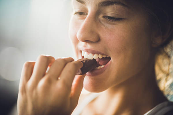 Woman eating a piece of candy.