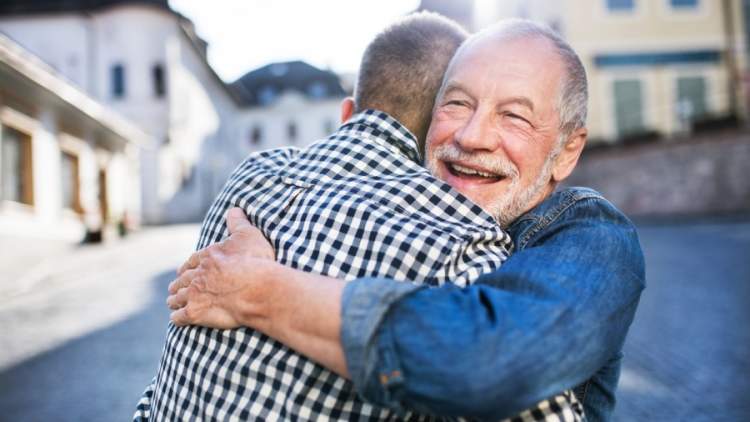 一个时髦的成年儿子和他年长的父亲在镇上拥抱。