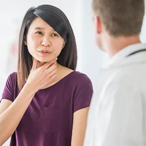 Woman discussing throat pain with her doctor.