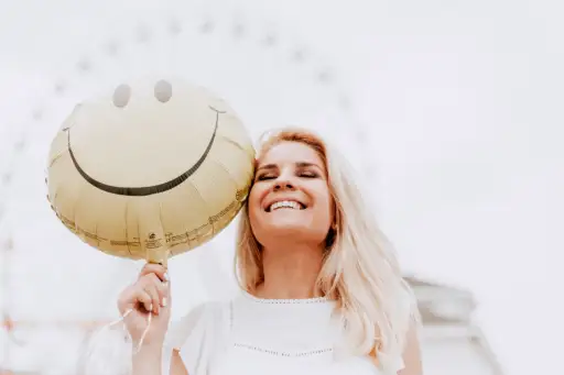 女人微笑着拿着笑脸气球